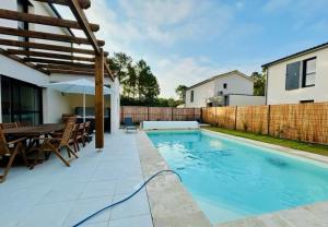 a swimming pool in a backyard with a wooden table and chairs at La Forêt d'Armotte villa 12 By Avecoeur in Saint-Augustin