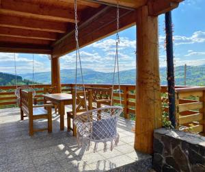 a porch with a swing and a table and chairs at Rezydencja Zawoja in Zawoja