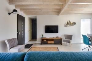 a living room with a blue couch and a tv at Maison pour 6 - Terrasse - 700 m de la Pointe in LʼHerbaudière