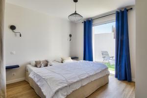 a bedroom with a bed with blue curtains and a window at Maison pour 6 - Terrasse - 700 m de la Pointe in LʼHerbaudière