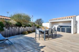 a patio with a table and chairs in a backyard at Maison pour 6 - Terrasse - 700 m de la Pointe in LʼHerbaudière