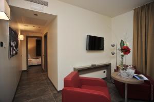 a hotel room with a red chair and a table at Klima Hotel Milano Fiere in Milan