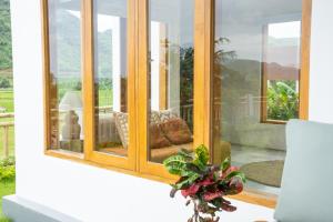 a vase of flowers on a table in front of a window at Villa Aura Lombok in Selong Belanak