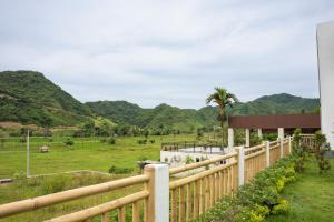a wooden fence with a field and mountains in the background at Villa Aura Lombok in Selong Belanak