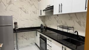a kitchen with white cabinets and a black counter top at Luxury Renovated Apartment in Agadir