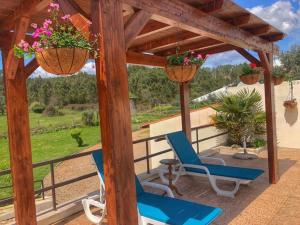 a patio with two chairs and two baskets with flowers at Casa Lerryn in Sertã