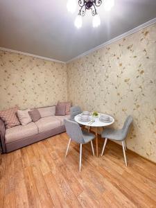 a living room with a couch and a table and chairs at Apartment on Bukhar Zhyrau in Karagandy
