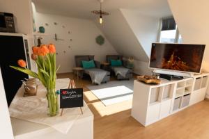 a living room with a television and a vase of flowers at Lake Breeze Maisonette in Leipzig, Balkon und See in Markkleeberg