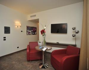 a living room with two red chairs and a tv at Klima Hotel Milano Fiere in Milan