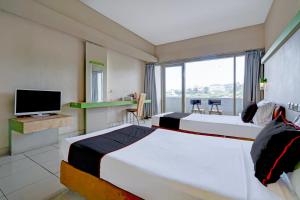 Una habitación de hotel con dos camas y un televisor. en Collection O Lembang Near Dusun Bambu Formerly Hotel Bilique, en Bandung