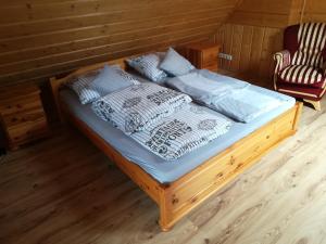 a wooden bed in a room with a chair at Domek Julia Mikoszewo in Nickelswalde