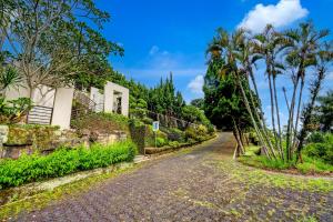 un camino vacío frente a una casa con palmeras en Collection O Lembang Near Dusun Bambu Formerly Hotel Bilique, en Bandung