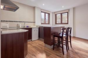 a kitchen with a bar and some chairs in it at Valle del Ibias - Primero Izquierda in Cecos
