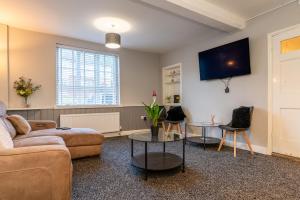 a living room with a couch and a tv on the wall at Airfield Manor in Castle Donington