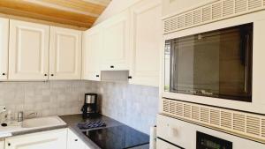 eine weiße Küche mit Spüle und Mikrowelle in der Unterkunft Le Rivage, maison proche mer avec Spa in Les Sables-dʼOlonne