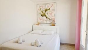 1 Schlafzimmer mit 2 weißen Betten und einem Gemälde an der Wand in der Unterkunft Le Rivage, maison proche mer avec Spa in Les Sables-dʼOlonne