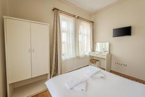 a white bedroom with a bed and a tv at Akuzun Stone Hotel in Ürgüp