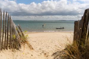 two people in the water on a beach with a boat at Camping La Pointe du Médoc in Le Verdon-sur-Mer +20 photos