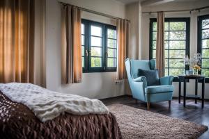 a bedroom with a bed and a chair and windows at Vakvarjú Csónakház by NW in Budapest +32 photos