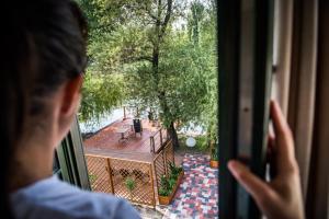 a man looking out of a window at a patio at Vakvarjú Csónakház by NW in Budapest