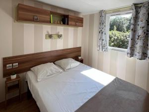une chambre avec un lit avec des draps blancs et une fenêtre dans l'établissement Camping La Pointe du Médoc, au Le Verdon-sur-Mer