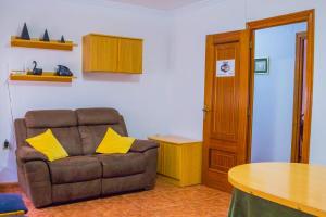 sala de estar con sofá marrón y almohadas amarillas en Apartamento Oran 2, en Castril