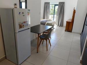 una cucina con frigorifero, tavolo e letto di Large Suite - Dream Den at Rustic Dune 3 a Jeffreys Bay