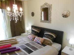 een slaapkamer met een bed met kussens en een kroonluchter bij Jardinas de les Marinas in Denia +58 foto's