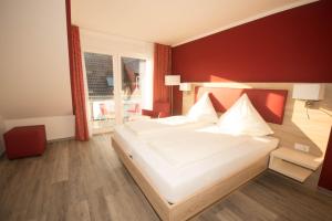 a bedroom with a large white bed and a window at Hotel Sonne am Meer in Norddeich
