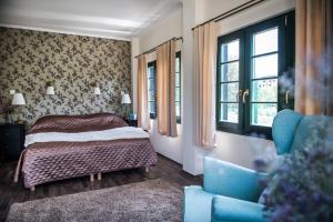 a bedroom with a bed and a chair and windows at Vakvarjú Csónakház by NW in Budapest