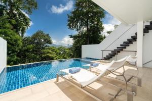 a swimming pool with two chairs and a table at Atika Villa 7 ocean view pool villa in Patong Beach