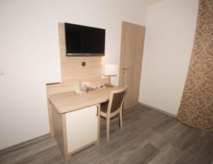 a room with a desk with a television on a wall at Hotel Sonne am Meer in Norddeich