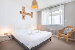 a bedroom with a large white bed and a chair at Rêve Bleu, 2 p, vue mer panoramique in Penmarcʼh