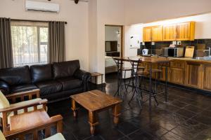 a living room with a leather couch and a kitchen at Phalaborwa Safari Park, A Forever Resort in Phalaborwa