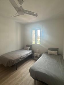 een kamer met twee bedden en een plafondventilator bij Casa Pom at the Beach in Torre de Benagalbón