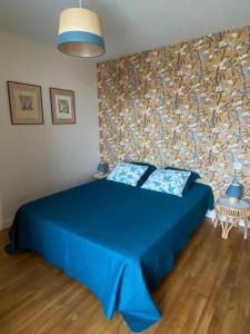 a bedroom with a blue bed and a stone wall at Maison - Au bord de la Dordogne - Périgord in Castelnaud La Chapelle