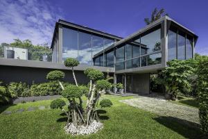 a large glass house with a garden in front of it at Villa Onyx in Amphoe Koh Samui