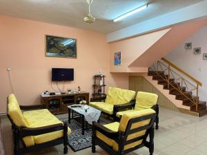 a living room with yellow furniture and a staircase at B'Mar Homestay in Tawau