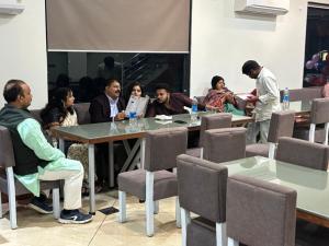a group of people sitting around a table in a room at Hotel Omkareshwar Inn in Deoghar