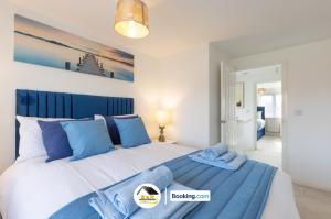 a bedroom with a large bed with blue pillows at Duckett house, 3 Bedroom Detached House By B and R Serviced Accommodation Amesbury With Free Parking in Amesbury