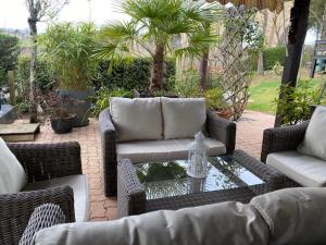 a patio with wicker furniture and a table with a bottle on it at Chambre avec terrasse in LʼIsle-Jourdain