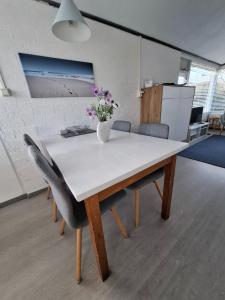 a table with chairs and a vase with flowers on it at Rekerlanden 90 in Schoorldam