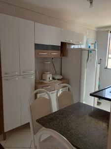a kitchen with white cabinets and a table and chairs at Salinópolis Praia in Salinópolis