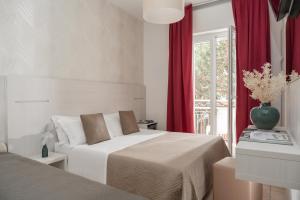 a bedroom with two beds with red curtains and a window at Hotel San Marco in Milano Marittima +55 photos