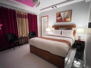 a bedroom with a large bed and red curtains at Nook House - Valley View Villa in Murree