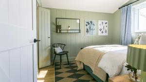 a bedroom with a bed and a chair and a mirror at 49 Wexham in Beaumaris