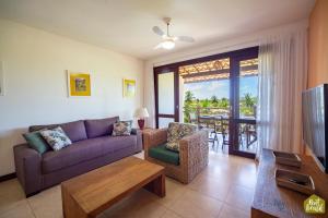 a living room with a couch and a table at Reserva Imbassaí - Apartamento TD 11 02 Superior - Buganvílias in Imbassai