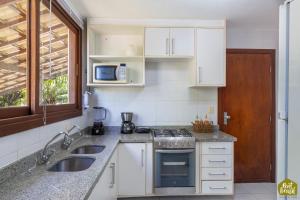 a kitchen with a sink and a stove top oven at Reserva Imbassaí - Apartamento TD 11 02 Superior - Buganvílias in Imbassai