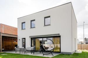 a white house with a patio with a swing at Sauna Moments Villa in Torhout