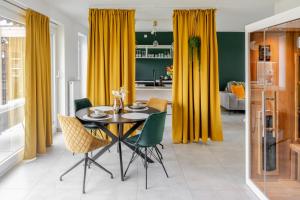 a dining room with yellow curtains and a table and chairs at Sauna Moments Villa in Torhout